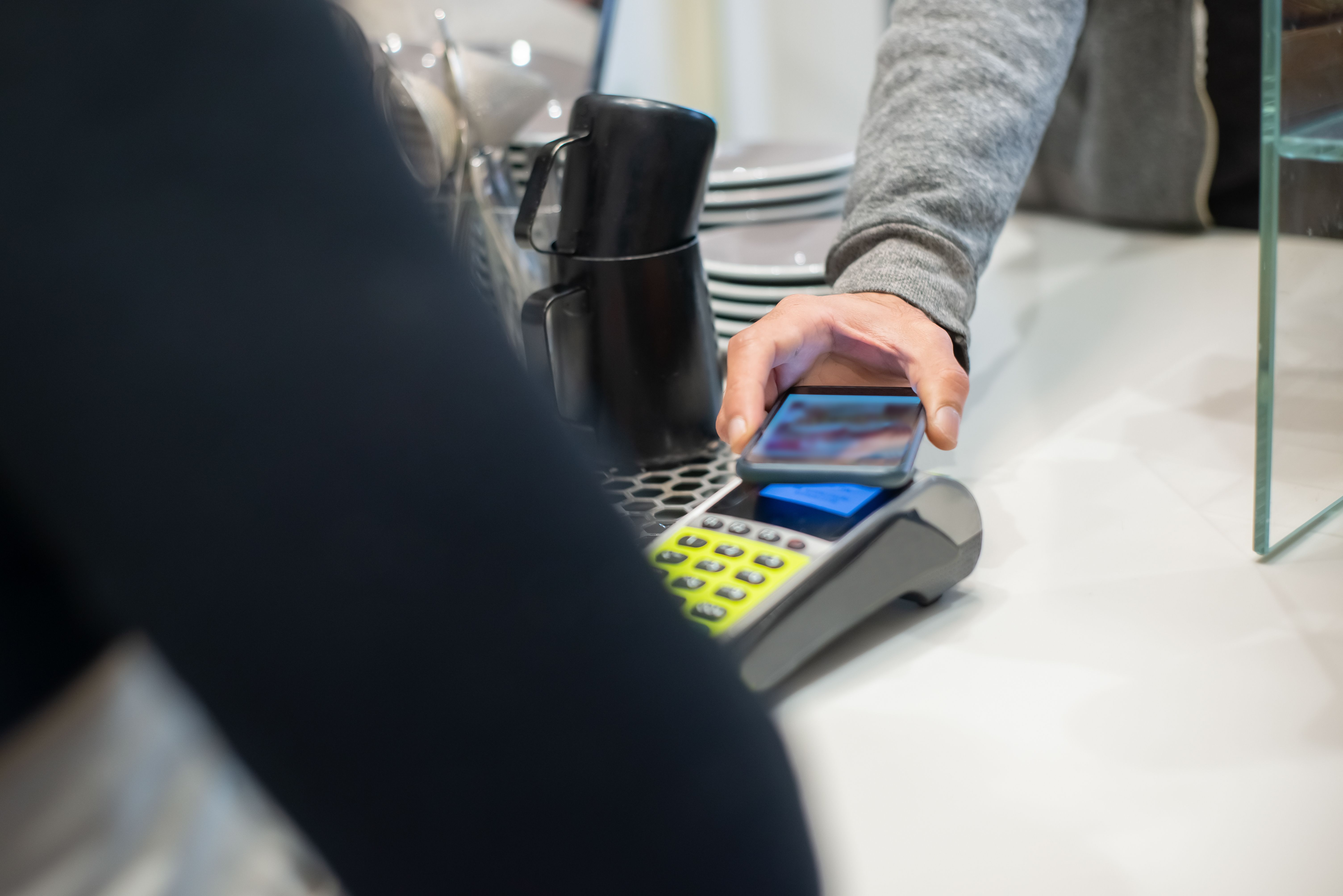 Customer making a contactless payment using a smartphone at a cafe