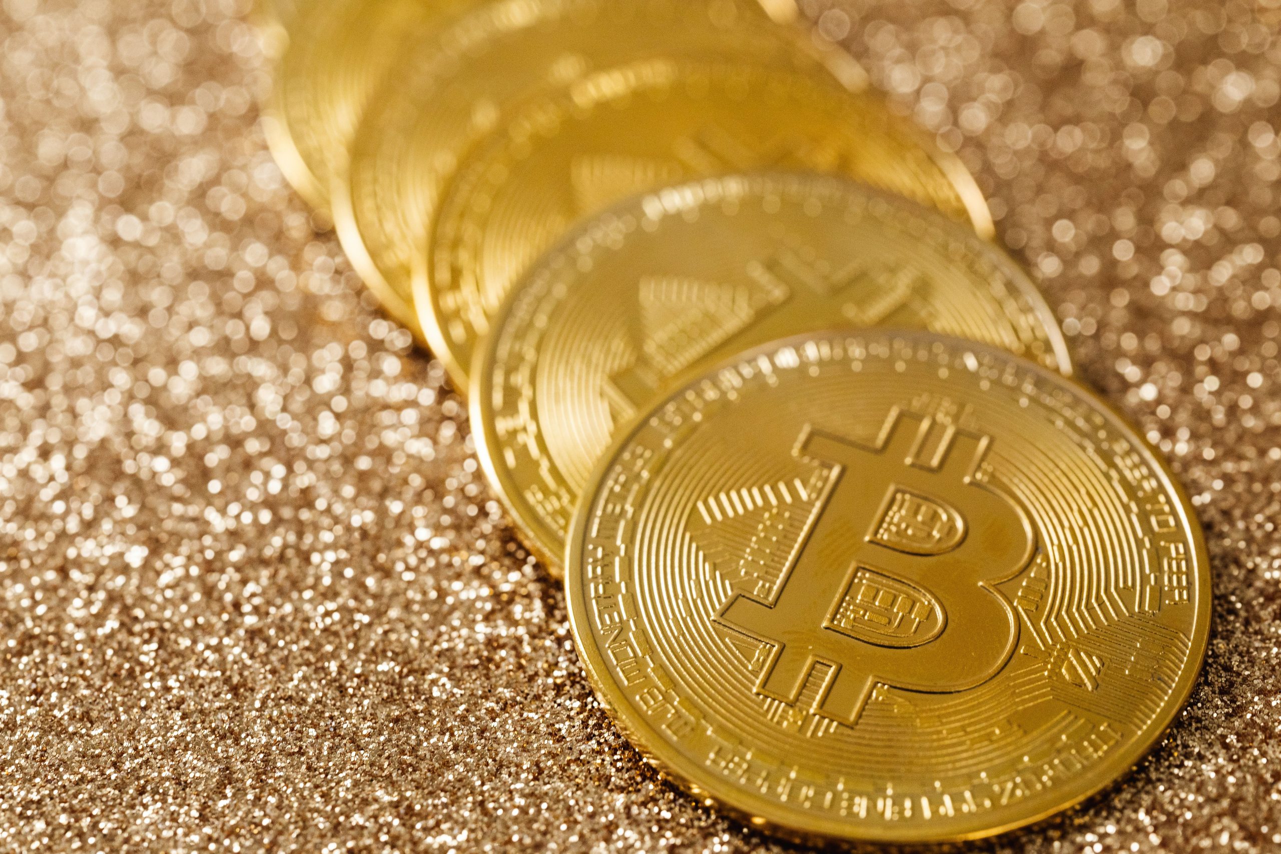 Close-up of golden Bitcoin coins on a shimmering glitter background, symbolizing cryptocurrency payments in online entertainment