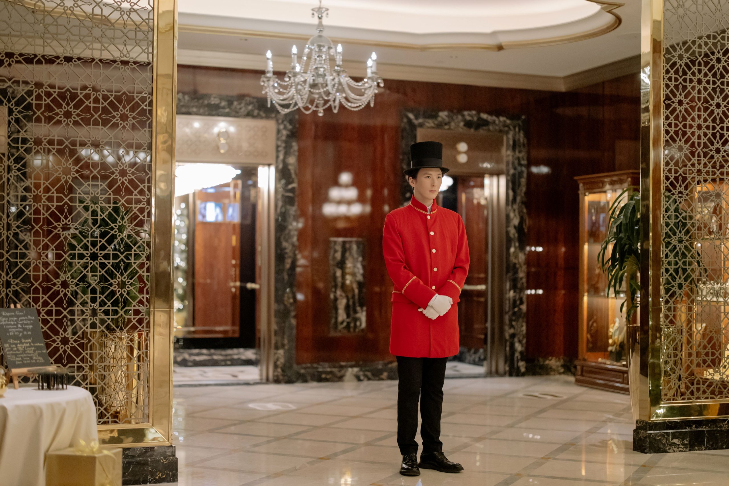 Uniformed hotel doorman ready to welcome guests in an elegant luxury lobby