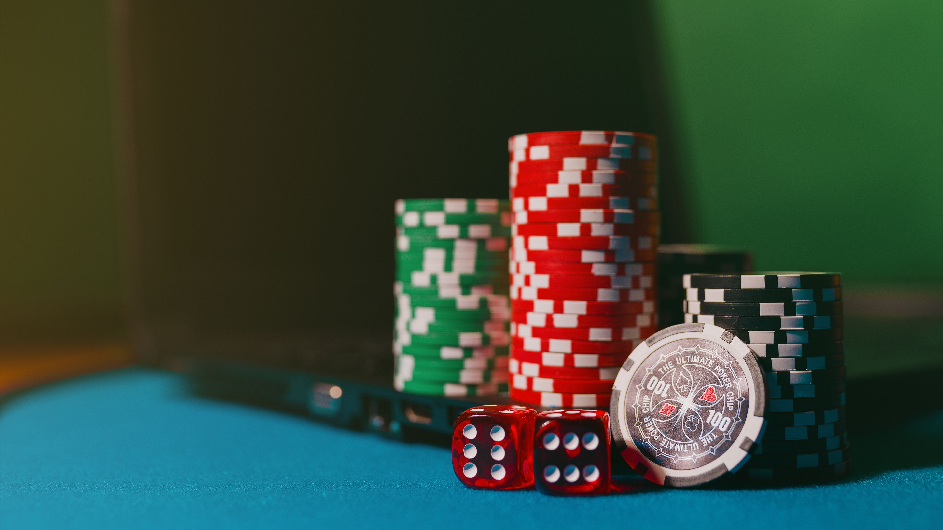 Casino chips and dice on a felt table next to a laptop for online gambling entertainment