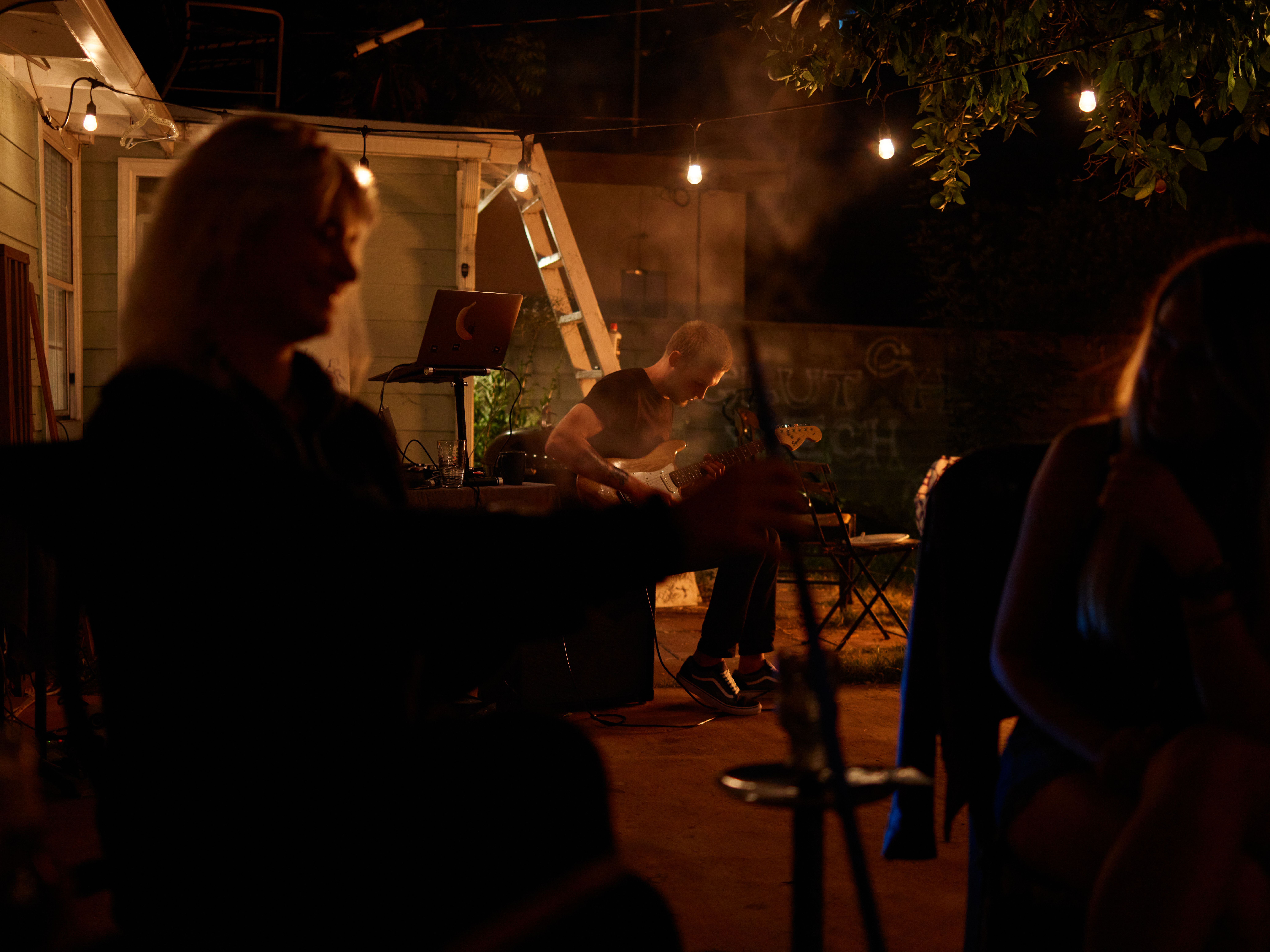 Relaxed backyard jam session with guitar and warm nighttime lighting