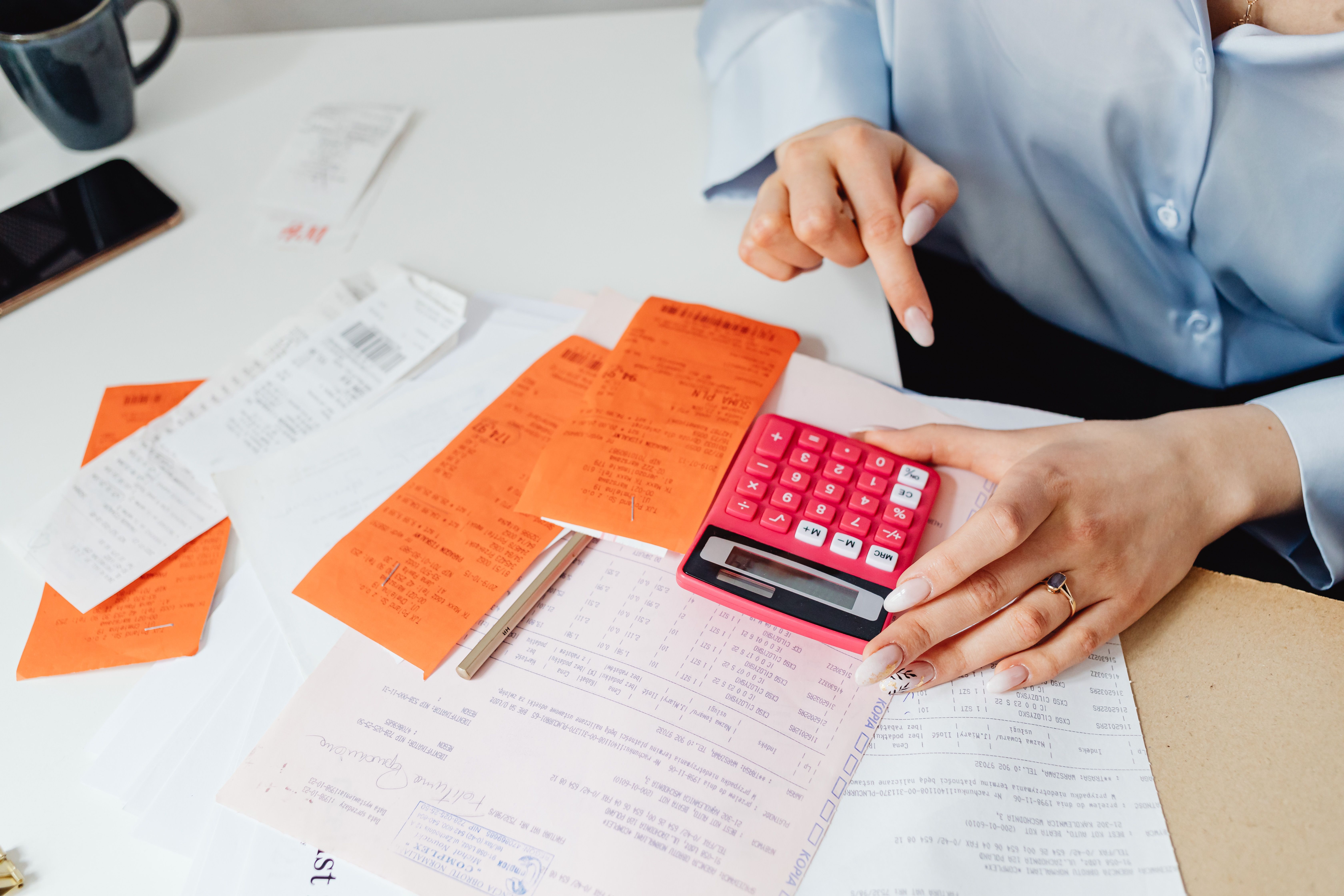 Businesswoman calculating expenses with receipts and a calculator at her desk