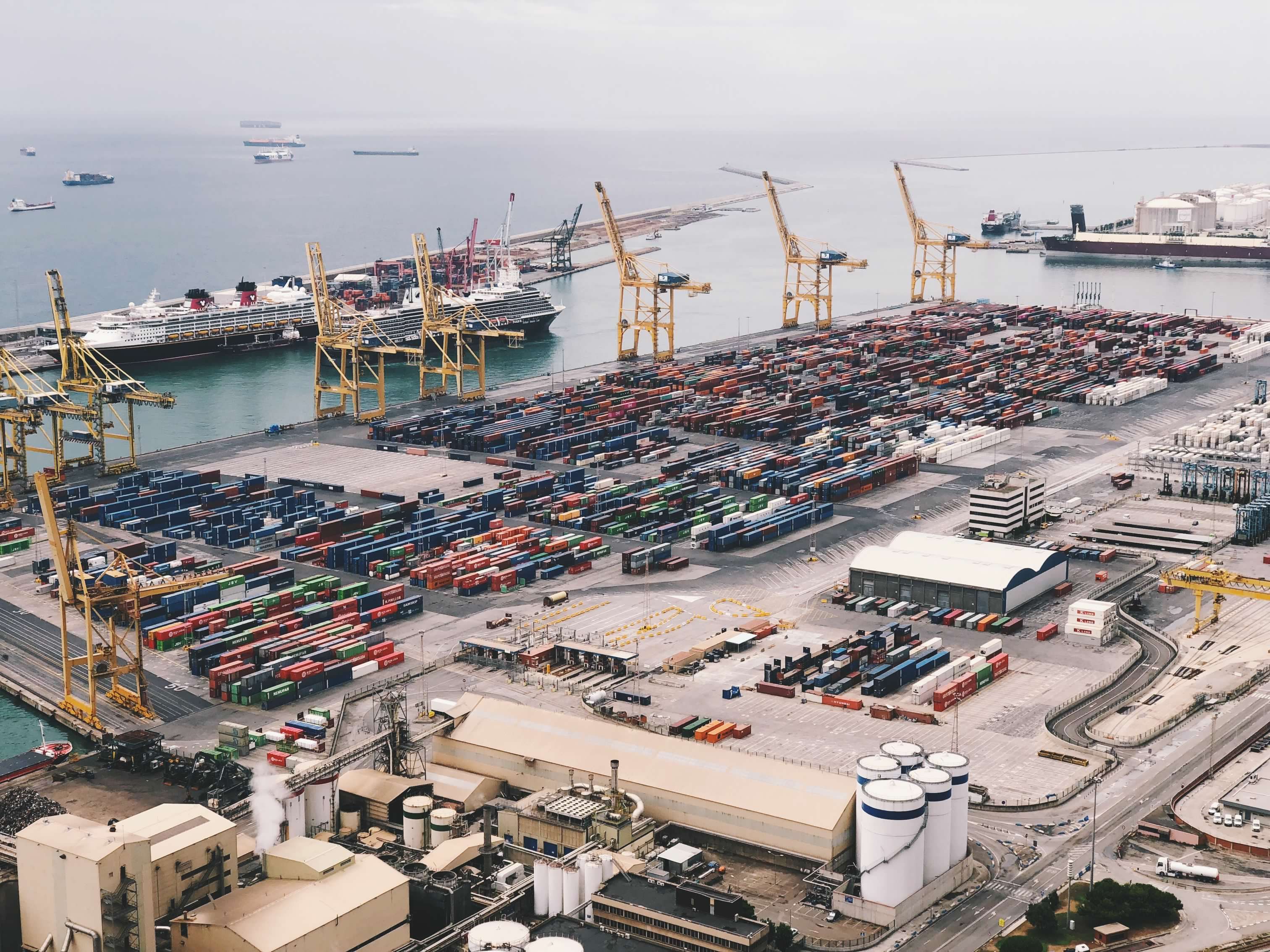 Aerial view of container ships and cranes at a busy global trade port.