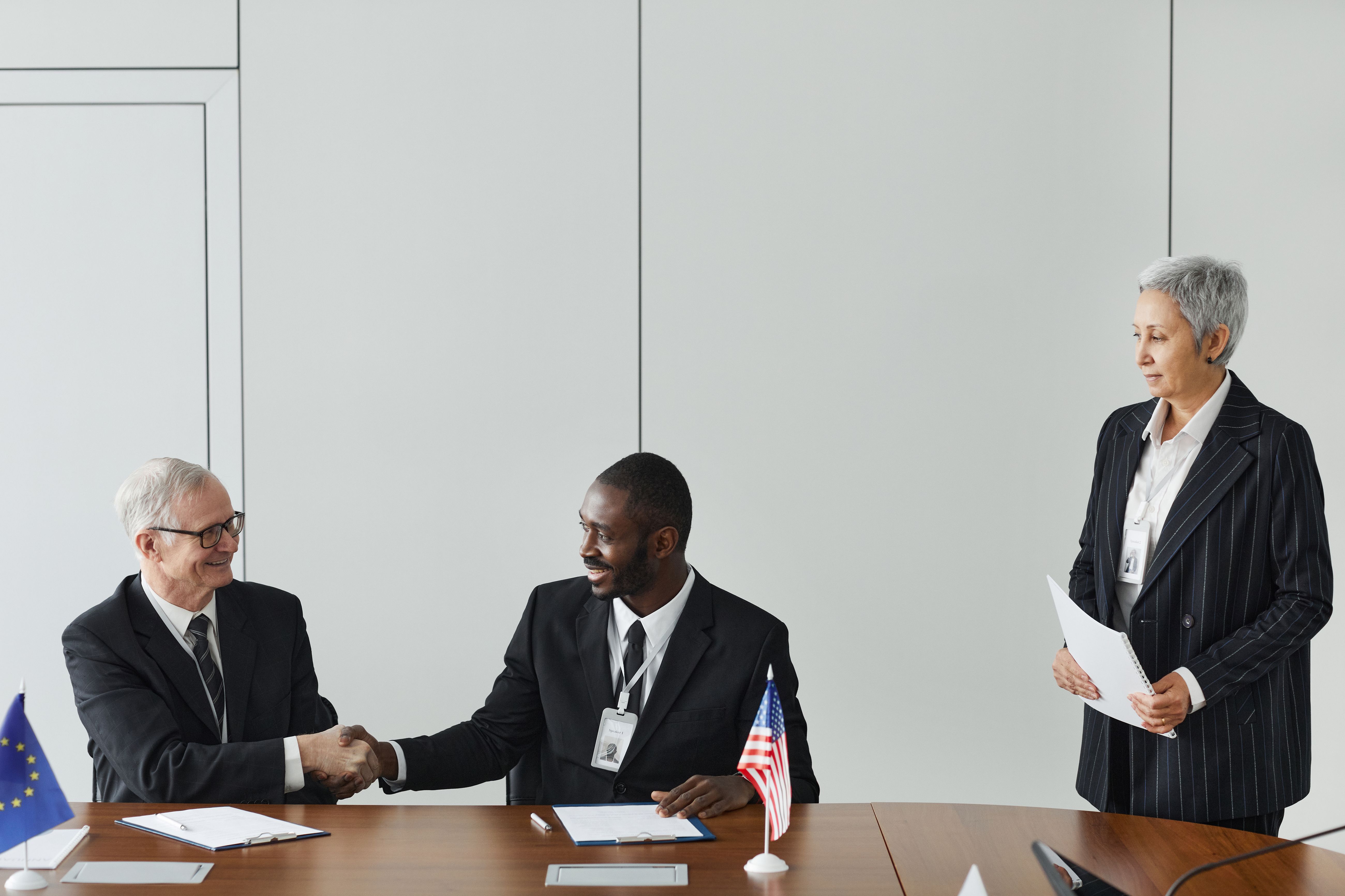 Multinational professionals signing an agreement at a business meeting with international flags.