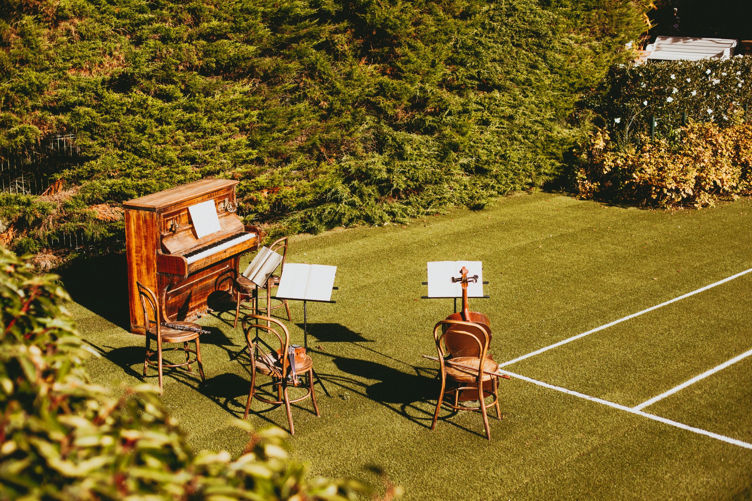 Outdoor piano and chairs arranged on a grassy lawn for a small music performance